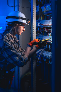 Female electrician installing wiring in electrical panel. Industrial maintenance work