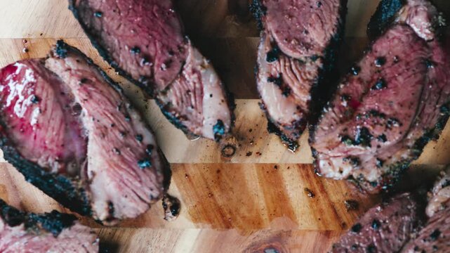 Sliced roasted lamb showing a juicy tender interior and seasoned crust, served on a rustic wooden board. Rich textures, warm tones and gourmet presentation perfect for menus and food content.