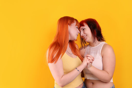Lovely lesbian couple on yellow background, space for text. LGBT concept
