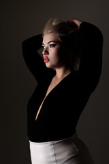 Fototapeta premium Model poses elegantly with hands in hair against dark background