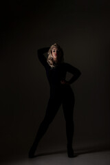 Fototapeta premium Model poses in dark setting with dramatic lighting and strong silhouette showcasing fashion style