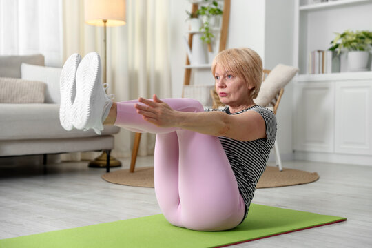 Senior woman exercising on mat at home. Fitness and sport