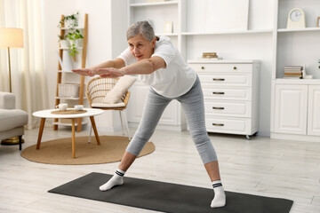 Obraz premium Senior woman exercising on mat at home. Fitness and sport