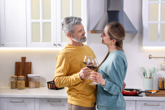 Lovely couple with glasses of wine in kitchen