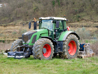 Obraz premium Modern green tractor on field, agricultural machinery in rural countryside