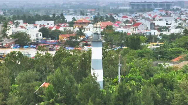 Cua Dai Lighthouse stands tall amidst lush greenery in Hoi An, Vietnam, guiding ships and illuminating the coastal landscape. A beacon of hope and safety for mariners.