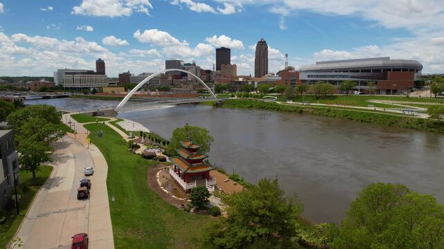 DES MOINES - 6.24.2024 - Very good aerial view moving over a river towards a curved bridge in downtown Des Moines, Iowa.
