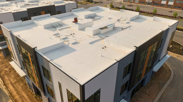 Aerial drone inspection of commercial TPO roof featuring heat-welded seams, HVAC curb flashing, and pipe penetrations.