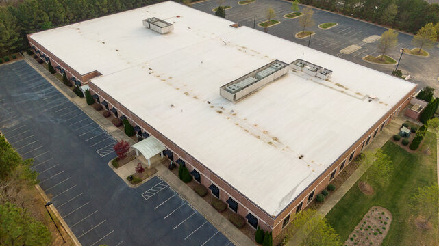Aerial drone view of a clean white TPO roofing membrane installation on a large industrial commercial building.