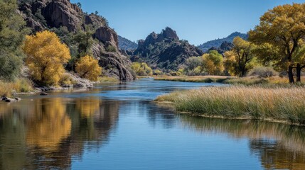 Obraz premium Scenic river flowing through a valley with mountains and vibrant autumn trees