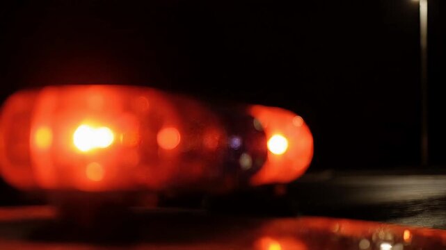 Dynamic motion blur captures the intense glow of rotating red emergency lights at night, symbolizing a critical event requiring immediate attention and rapid response