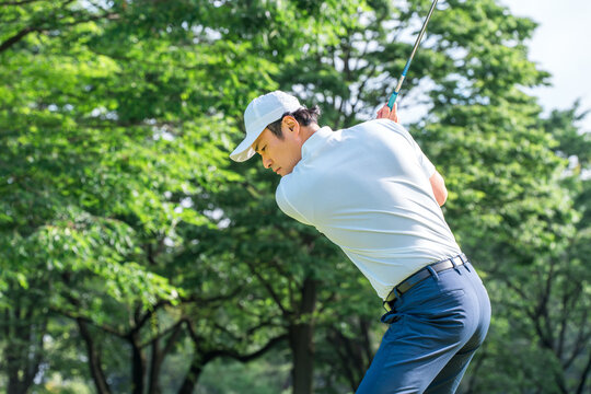 A male golfer hitting a tee shot on a golf course (golf swing)