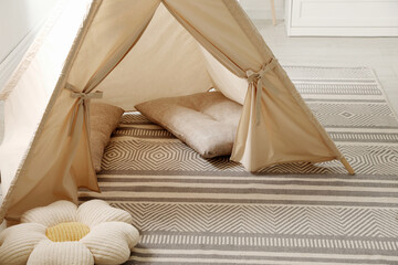 Stylish toy wigwam and pillows on floor in playroom. Interior design © New Africa