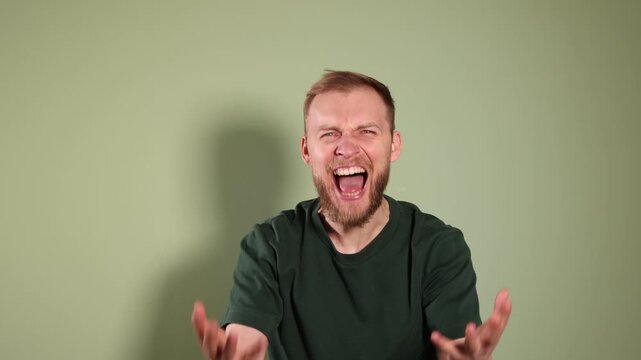 Resentment. Angry man screaming on olive background
