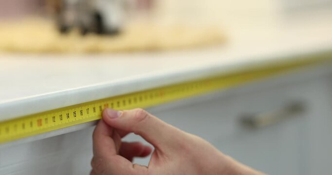 Man measuring countertop with tape indoors, closeup. Camera moving in