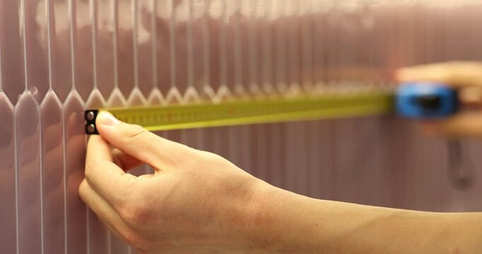 Man measuring peel and stick tales with tape indoors, closeup