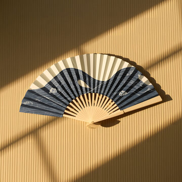 Minimalist view of a traditional Japanese folding fan (Sensu) with elegant dark blue and white wave patterns on a clean light brown background