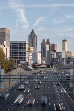 View of the Downtown Atlanta Skyline Cityscape showing several prominent buildings, highways, cars, and hotels on a beautiful clear evening as seen from a city street.
