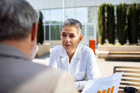 Senior doctor consulting patient outdoors at clinic