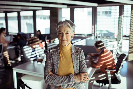 Confident senior businesswoman leading team in modern office