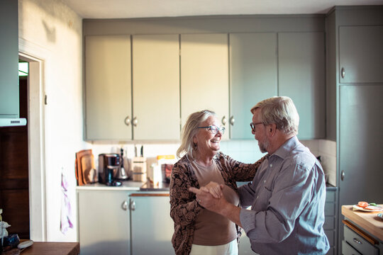 Senior couple dancing together in home kitchen