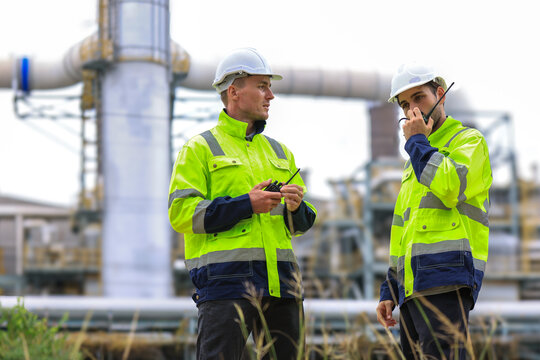 Engineers workers with tablet in a refinery - oil processing equipment and machinery, Industry zone gas petrochemical. Factory oil storage tank and pipeline. Workers in the refinery construction.