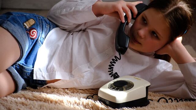 Teenager girl with a vintage rotary phone, lying on the floor and talking, smiling, whispering.  Pretty teenager girl talking with friend