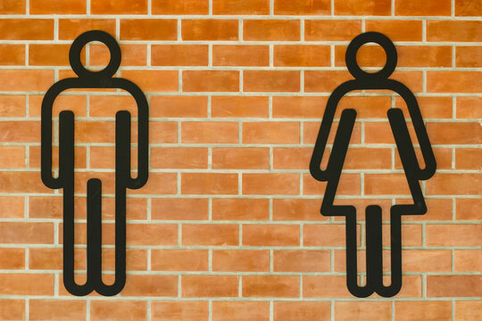 The symbols for the men's and women's restrooms are attached to the warm orange brick wall.