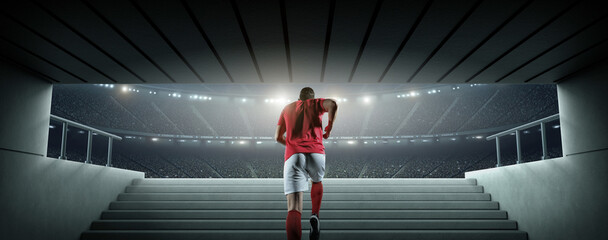 Rear view of a football player walking out of the tunnel onto the pitch. An imaginary soccer stadium is modelled and rendered. © efks