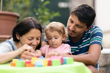 Obraz premium Happy family playing indoors together with colorful blocks and toys