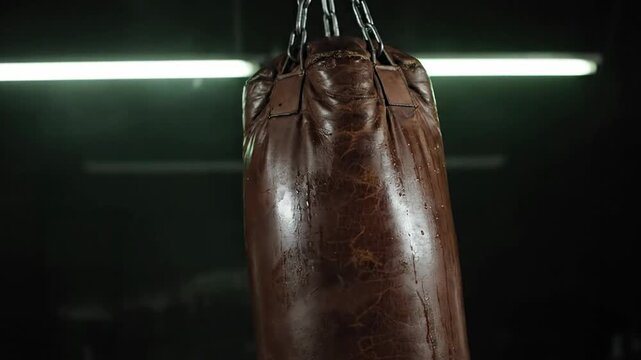 Brown Leather Punching Bag Hanging in Gym with Overhead Lights