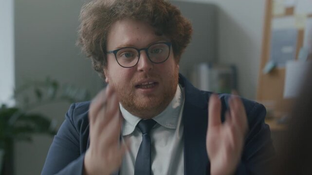 Male manager explaining business tasks and key points to employee sitting across from him in office during professional meeting