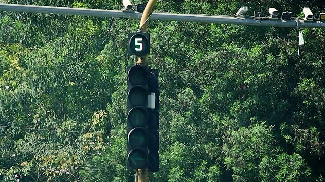 Traffic signal with green arrows and signal change sequence at urban road junction, useful for transport, road safety, navigation and smart city themes.