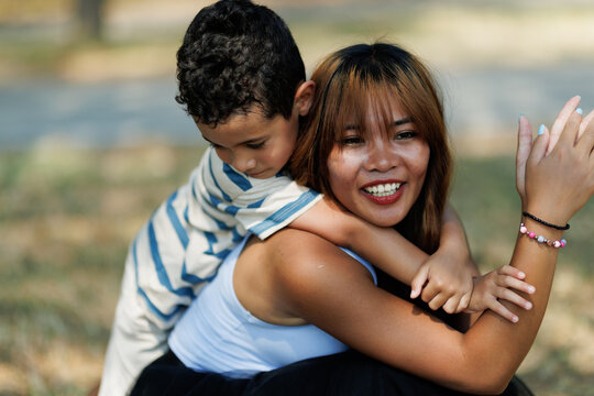 Joyful mother and young child embrace outdoors, symbolizing affection and family bond