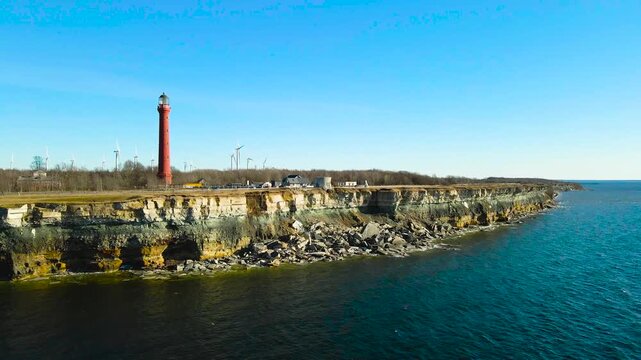 Stunning aerial footage revealing the historic pakri lighthouse and a modern wind farm situated on the beautiful and rugged limestone cliffs of the paldiski peninsula in estonia