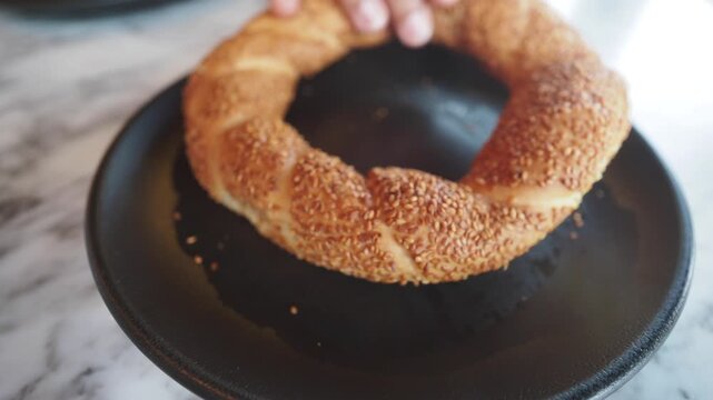 Fresh simit with sesame seeds on a black plate