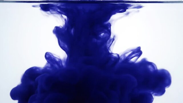 Dark blue ink cloud dissolving in clear water, abstract motion, slow motion