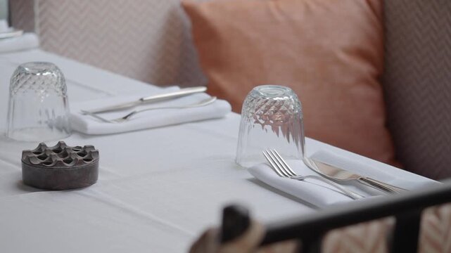 Table setting for dinner in restaurant with silverware and glass.