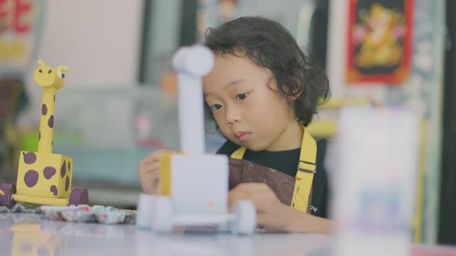 Young child learning painting while decorating a plaster figurine with a brush, developing artistic skills, creativity, concentration, imagination.