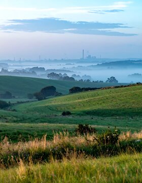 A serene landscape with rolling green hills and foggy cityscape distance