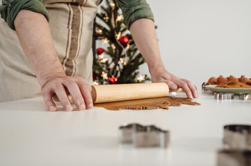 Obraz premium Side view on man rolling out the dough preparing cookies for chrismas