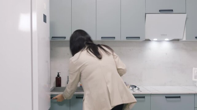 White woman prepping salad at round table, arranging chopped cucumber and tomatoes onto plates, then moving to open refrigerator in tidy pastel kitchen, practical meal prep routine