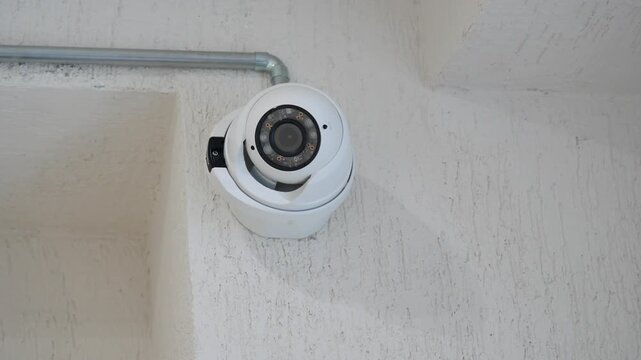 A close-up view of a security camera captures its subtle movements as it monitors an area, showcasing modern surveillance technology in action.