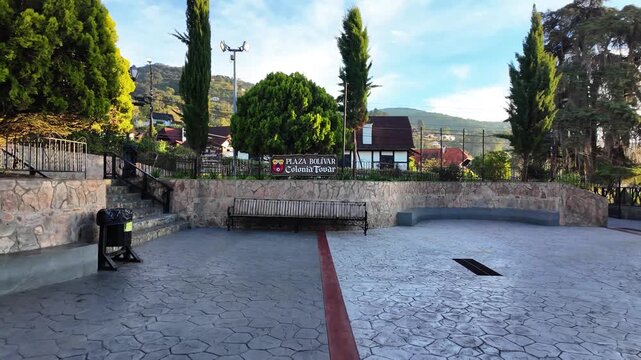 Cinematic dolly-out video of the historic Plaza Bolivar in Colonia Tovar, showcasing the official landmark sign and traditional mountain architecture.