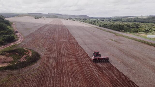 Case IH tractor with precision planter seeding crop in Formosa, Goi&aacute;s, Brazil showing contrast between planted rows and prepared soil, large-scale agribusiness operation near cerrado vegetation aerial