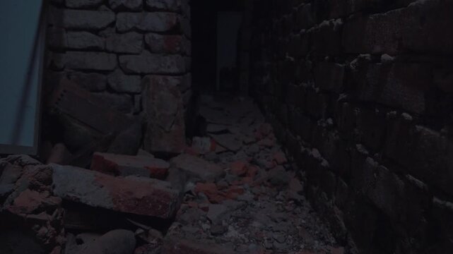 An abandoned brick-walled basement, illuminated by flickering light of a broken lamp. The dirt floor is littered with brick fragments and debris. The scene is dark and eerie. The angle is from below