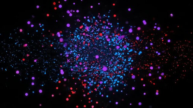 Colorful particles explode in darkness.