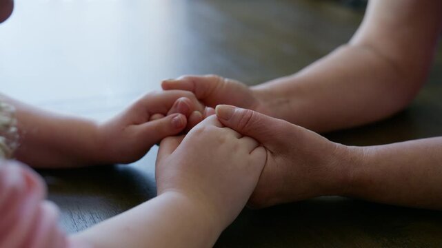 Close up shoot of Granddaughter gently holding her Grandmother hands, expressing love, care, family support, and intergenerational connection.