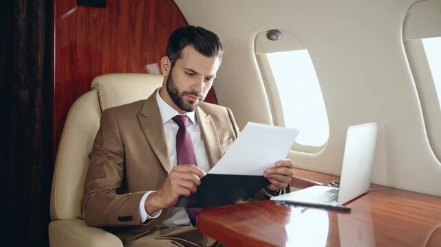 Businessman reviewing documents on private jet during luxury travel