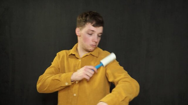 Man cleaning clothes with lint roller at home, closeup
